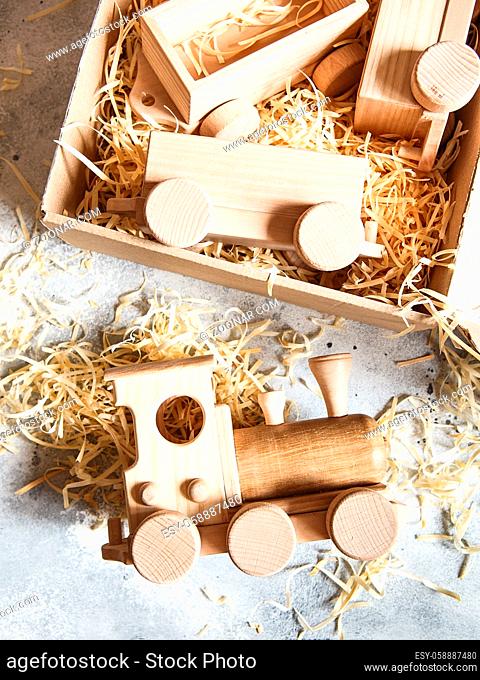 Children's wooden toys. Children wooden train with wagons in the box with sawdust. Natural wood construction set. Educational equipment