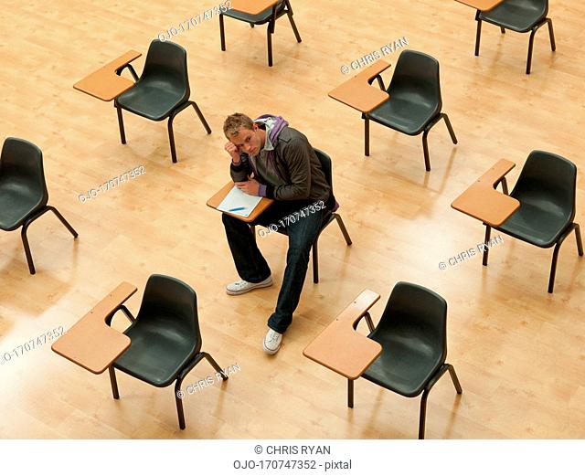 Pensive college student sitting at desk in classroom