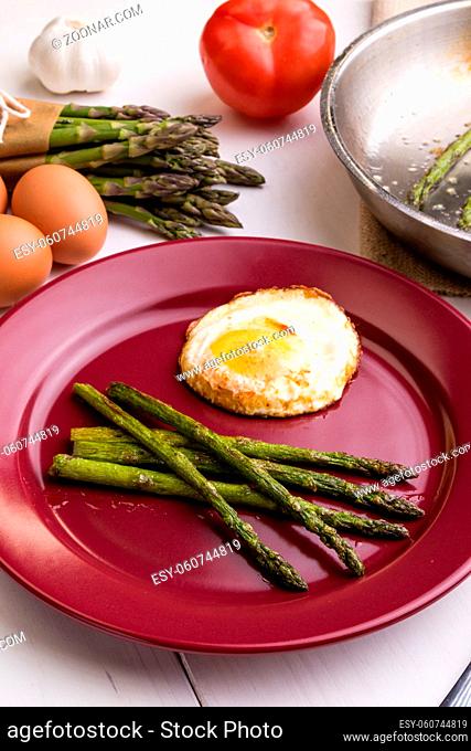 fried green healthy asparagus with egg on red plate