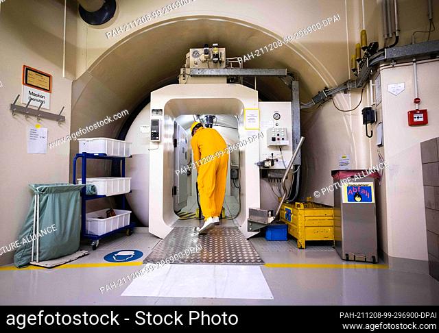 02 December 2021, Schleswig-Holstein, Brokdorf: An employee of the Brokdorf nuclear power plant pulls a material trolley out of the main airlock to the reactor...