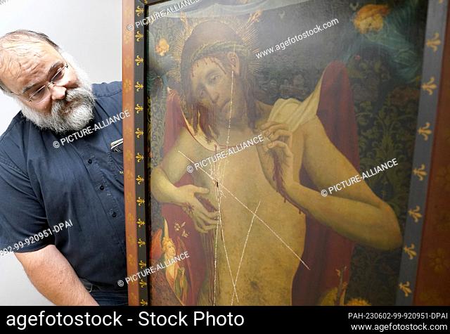 02 June 2023, Hamburg: Sexton Martin Meier stands next to the damaged painting ""Christ as Man of Sorrows"" in a room in the main church of St. Peter