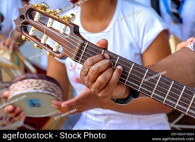 Detail of guitarist's hands and his acoustic guitar at an outdoor samba presentation