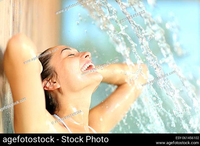 Happy woman enjoying and laughing under water jet in spa