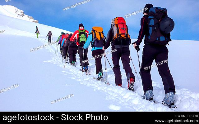 group of backcountry skiers crossing a glacier on their way to a high summit in the Alps of Switzerland on a beautiful winter day