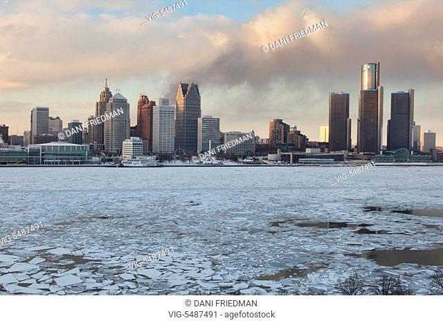 Smoke from a fire in an abandoned neighbourhood wafts behind the skyline of downtown Detroit, Michigan, USA. Chunks of ice can be seen floating along the...