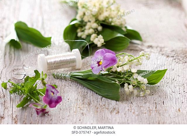 Tying posies of lilies of the valley and horned violets