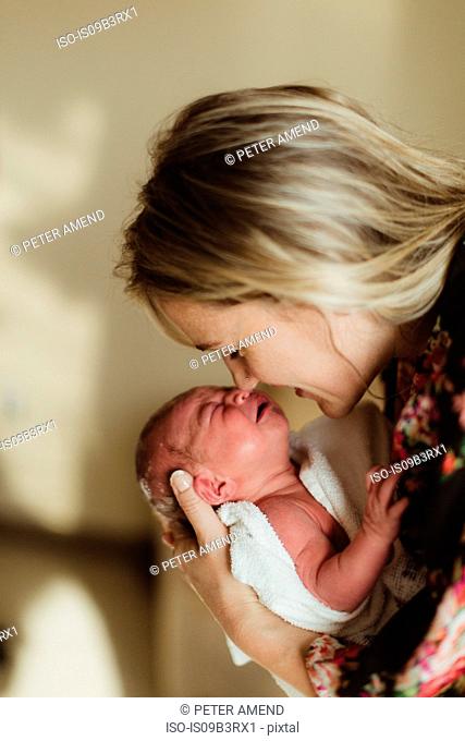 Mid adult woman nose to nose with newborn baby daughter