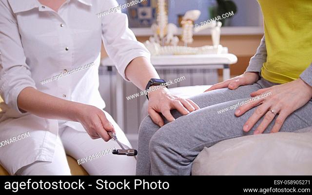 Doctor the neurologist examines the patient taps with a hammer on the knee, close up, health and medical concept