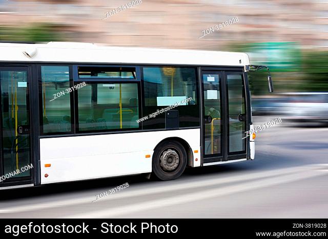 white city bus goes along street