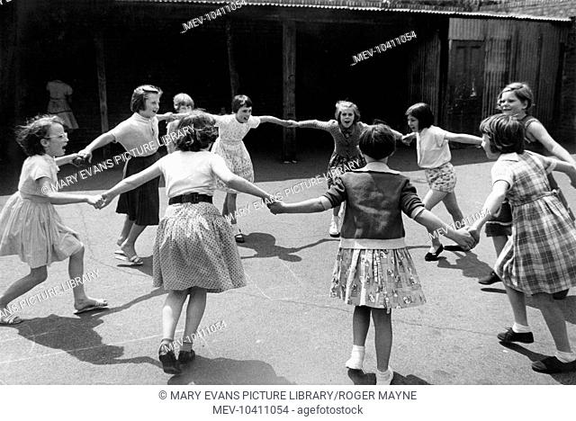 A group of girls playing a singing game called Hokey Pokey in the playground of St John's School, Kilburn, north west London
