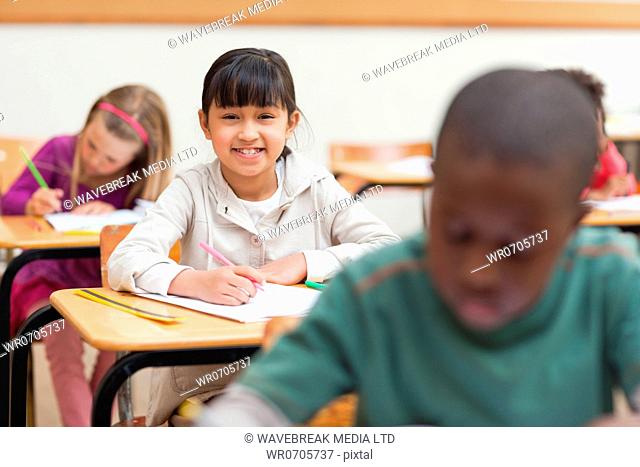 Little girl sitting at her desk in school