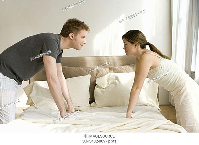 Couple facing each other across bed