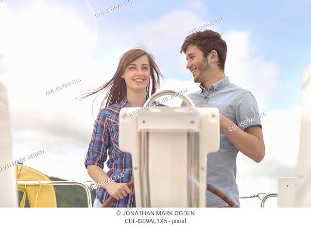 Young couple at the helm of yacht under bright sunlight