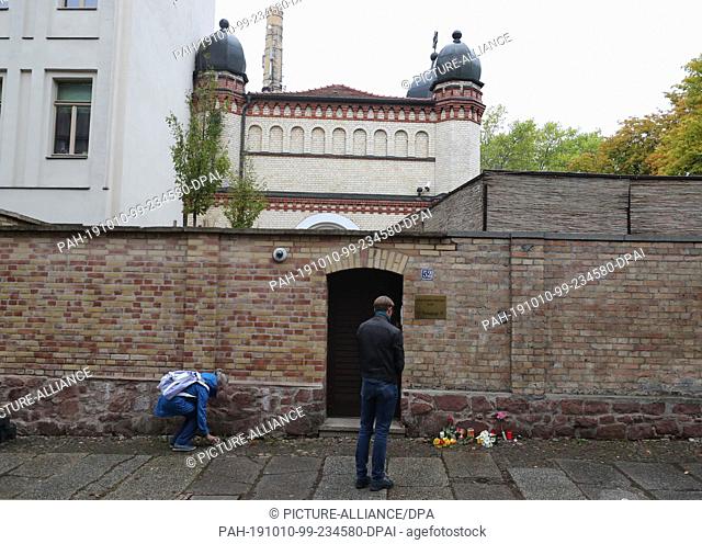 10 October 2019, Saxony-Anhalt, Halle: People lay flowers and candles in front of the synagogue. During attacks in the middle of Halle an der Saale in...