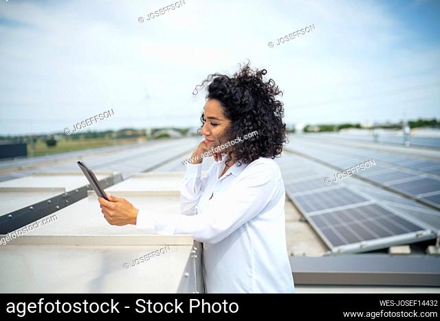 Businesswoman looking at tablet PC in front of solar panels on rooftop