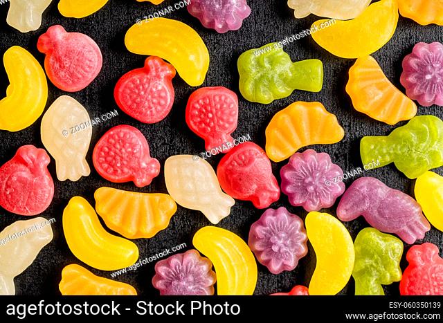Colorful fruity jelly candies on black table. Top view