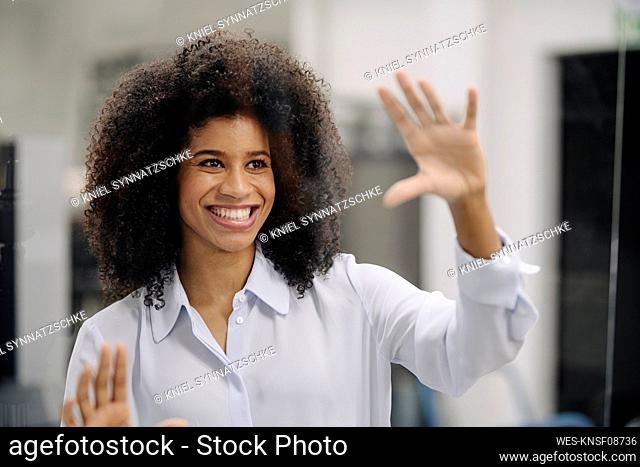 Smiling Afro businesswoman seen through glass in office