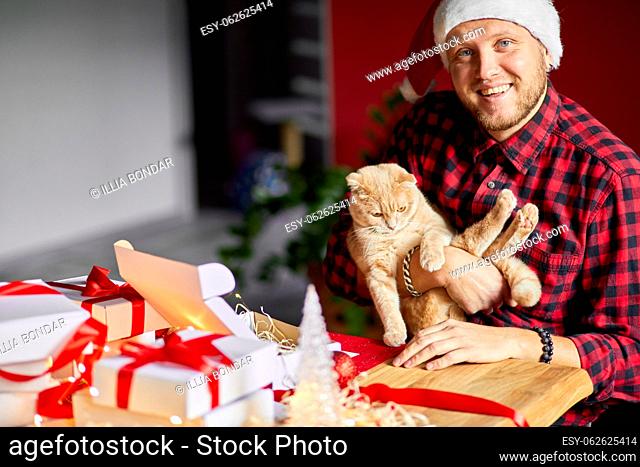 Vet Man in Santa hat and cat in hand making greeting card for New Year and Christmas, congratulation for clients or friends or family