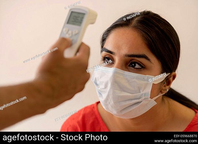 A woman's body temperature being checked using thermometer gun