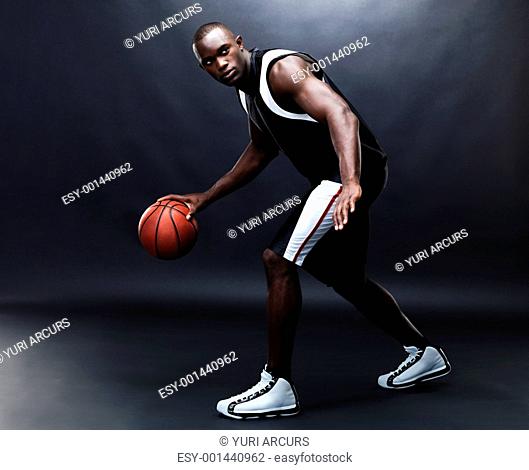 Portrait of a fit young male basketball player practising against grunge background