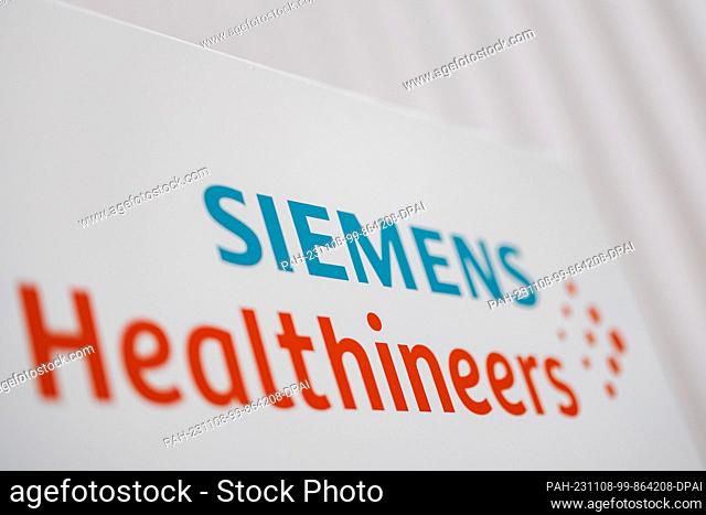 07 November 2023, Bavaria, Erlangen: The logo and lettering of the medical technology group Siemens Healthineers stands on a stele in front of the facade of a...