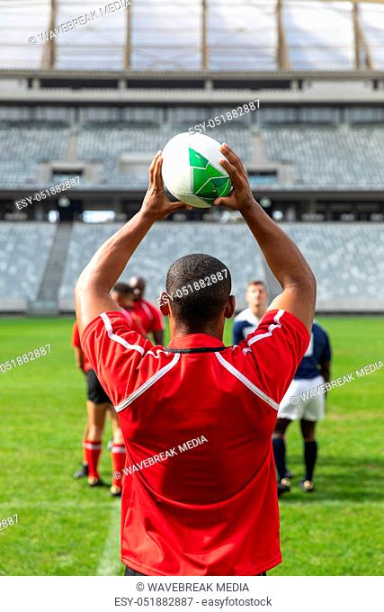 Male rugby player throwing rugby ball in stadium