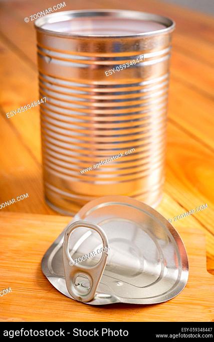 An open metal can on a kitchen wooden table. Food preserved in the household. Light background