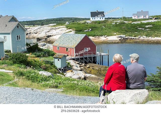 Canada Peggy's Cove Nova Scotia peaceful and quiet famous harbour with boats and homes in summer with older couple relaxing