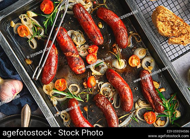 Delicious grilled sausages served on metal rusty tray. With barbecued vegetables, bread and mustard. Top view, flat lay