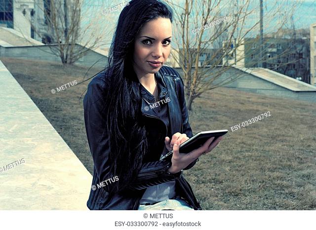 Brunette with tablet pc in autumn park looking at camera