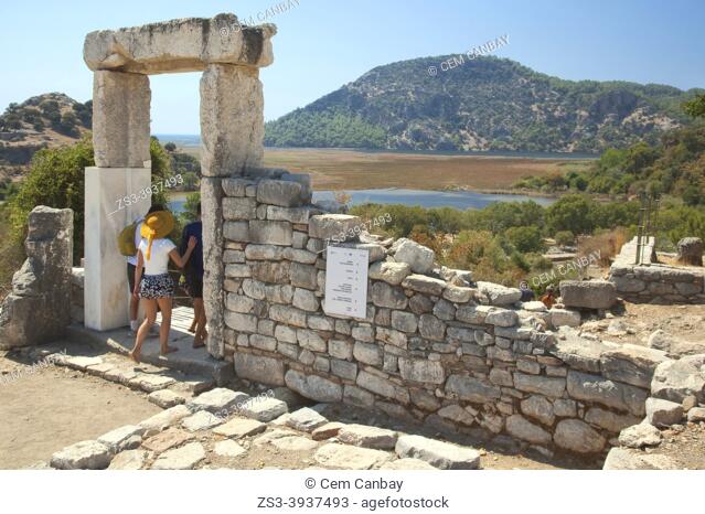 Tourists passing through an ancient door which is leading to The Fountain, Agora, Stoa, The Sacred Precinct Of Apollo and The Temple Terrace