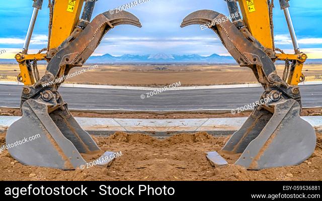 Tractor symmetry with open scooper on an excavator. At twilight with the excavortor pointing toward the center of the photo