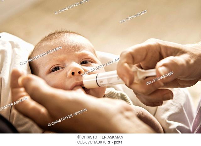 Parent feeding infant with syringe