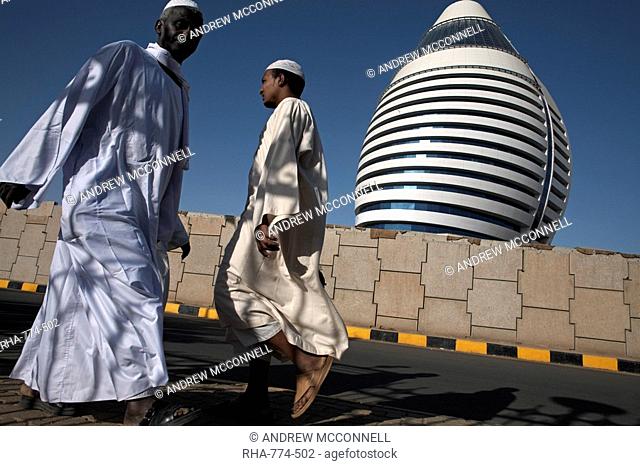 Locals walk past the 5-star Boji Al-Fateh Hotel Libyan Hotel, designed to represent a sail, Khartoum, Sudan, Africa