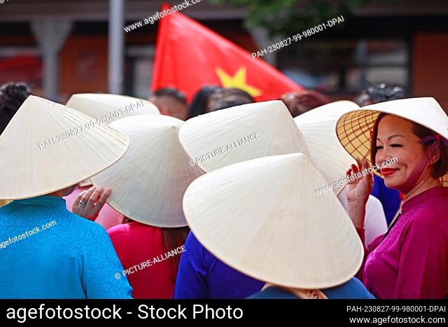 27 August 2023, Saxony-Anhalt, Wernigerode: Participants of a parade stand with Asian cone hats before the parade through the old town in Wernigerode