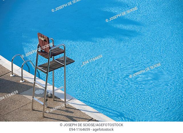 A partial view of a motel swimming pool showing water and an empty life guard stand