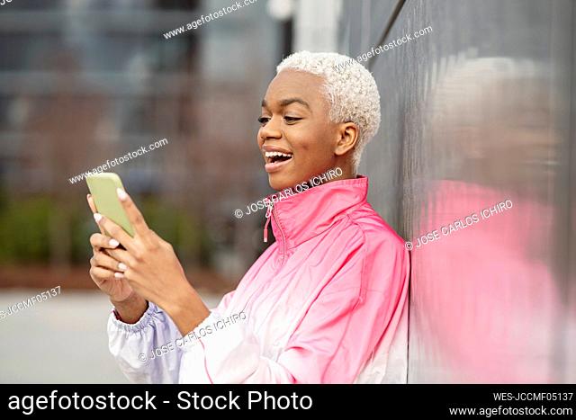 Surprised woman using smart phone in front of wall
