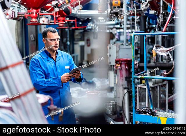 Male technician using digital tablet while working in factory