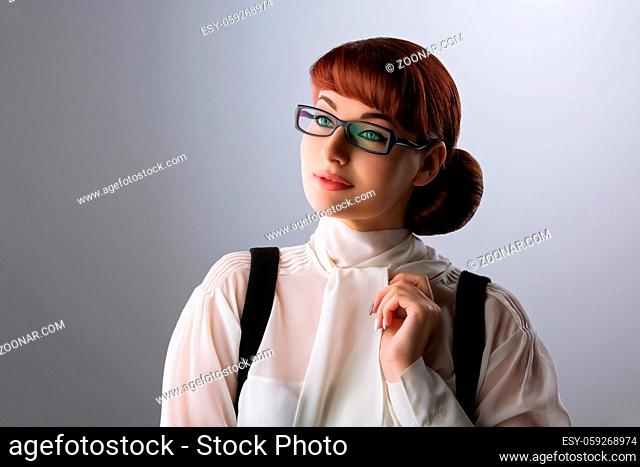 Closeup of beautiful young woman in white blouse and glasses over grey background