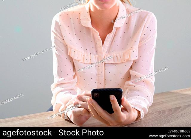 Midsection of caucasian businesswoman using smartphone, isolated on grey background