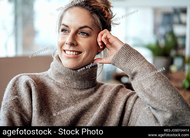 Thoughtful woman smiling while looking away in cafe