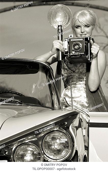 A fashion model holding an old camera