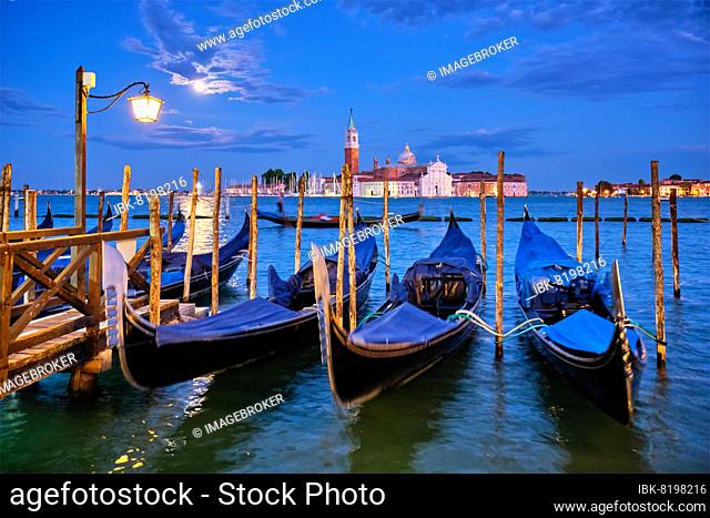 Romantic vacation Venice travel background, gondolas at Saint Mark (San Marco) square and Basilica San Giorgio Maggiore Church seen across Venice lagoon with...