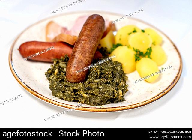 PRODUCTION - 25 January 2023, Lower Saxony, Oldenburg: A portion of kale with the traditional side dishes of boiled potatoes, boiled sausage