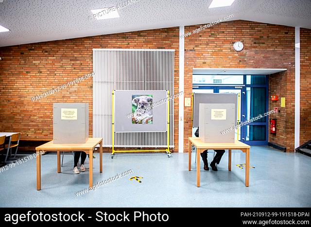 dpatop - 12 September 2021, Lower Saxony, Oldenburg: A voter sits in the polling booth in a polling station located in the foyer of an elementary school and...
