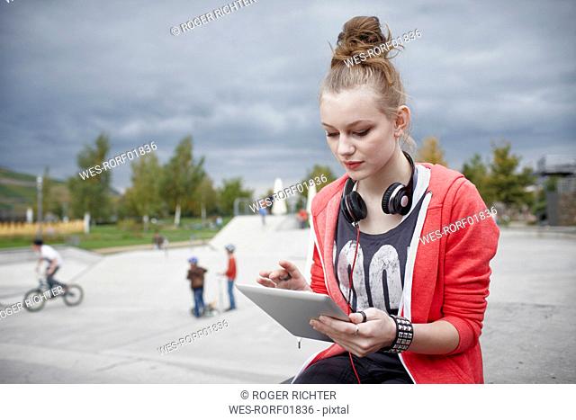 Teenage girl using a tablet at a skatepark