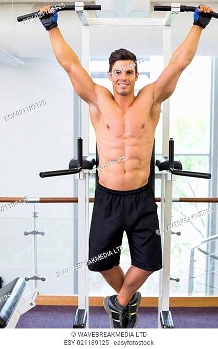 Shirtless male body builder doing pull ups