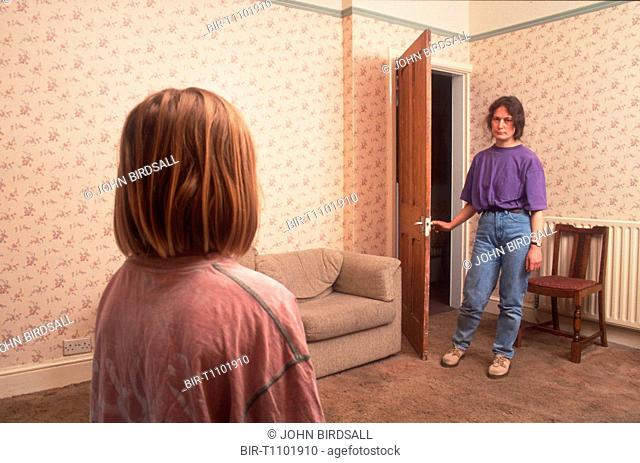 Mother standing in doorway of living room staring at young daughter who is standing opposite