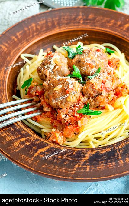 Meatballs in tomato sauce with parmesan and spaghetti in a brown ceramic plate, selective focus