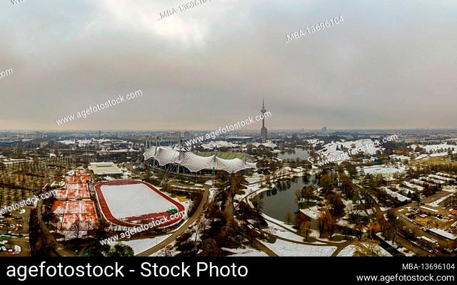 Winter in Munich, snow covered park in the heart of the bavarian metropole, a panoramic view at the olympic park with its tower and lake